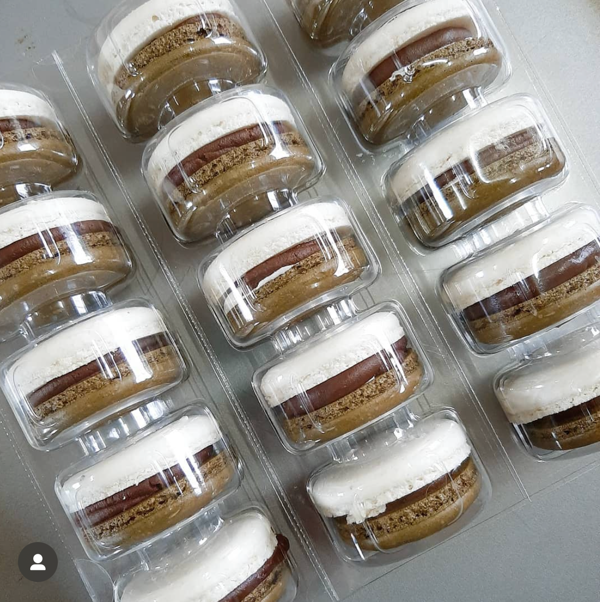 Packaged macarons with multiple layers in clear plastic packaging on a light gray background